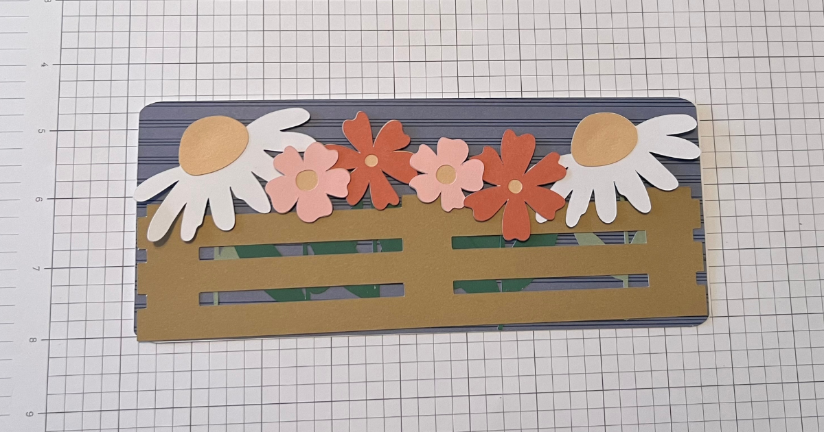 Slide the fence rail under the flowers on the Cricut card